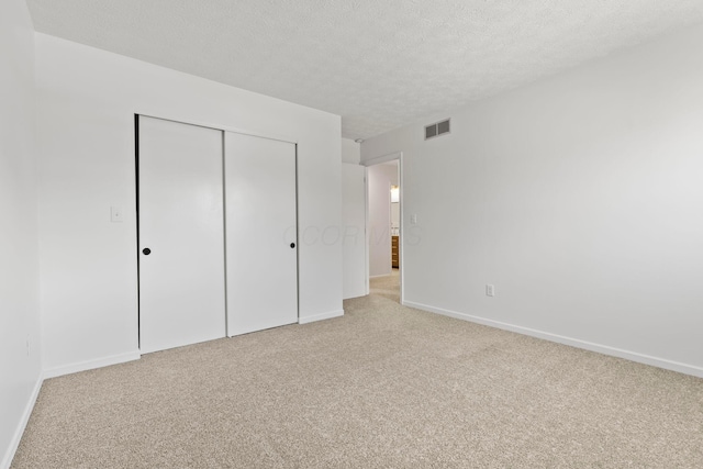 unfurnished bedroom with light carpet, a closet, and a textured ceiling