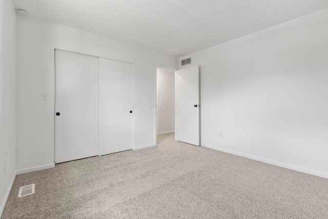 unfurnished bedroom featuring light carpet and a closet