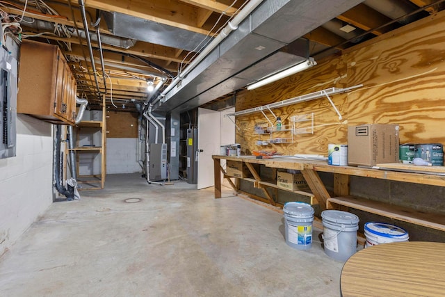 basement with a workshop area, electric water heater, and heating unit