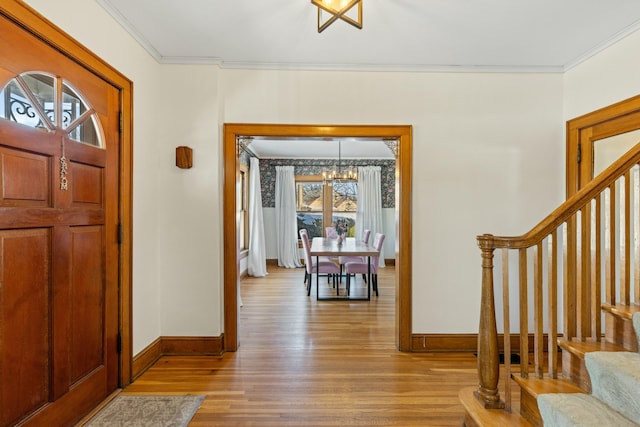 entryway featuring light wood-type flooring, ornamental molding, and a notable chandelier