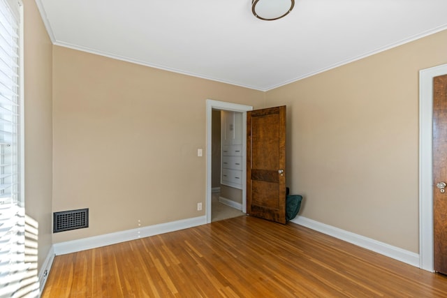 spare room featuring wood-type flooring and ornamental molding