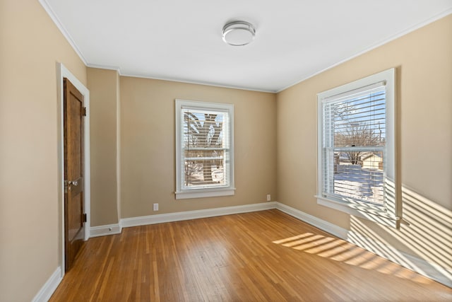 spare room with a wealth of natural light, crown molding, and wood-type flooring