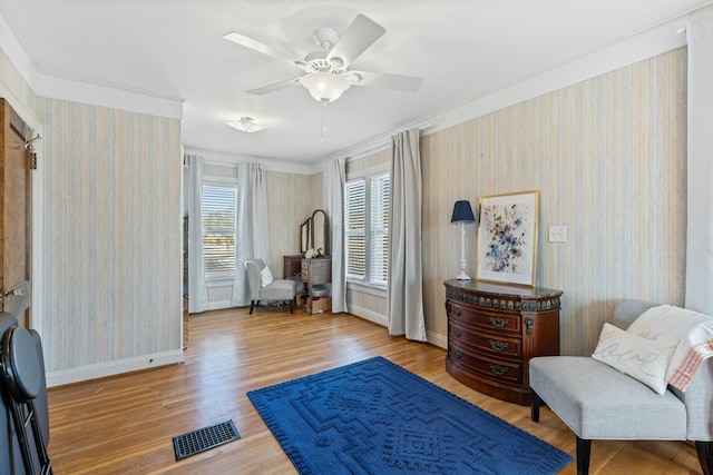 living area with ceiling fan, crown molding, and light hardwood / wood-style floors