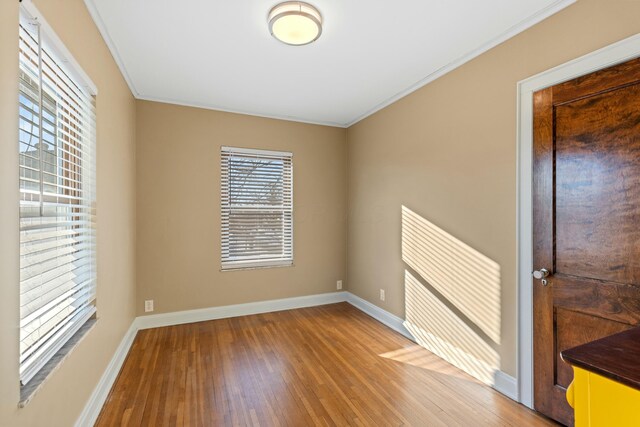 spare room with hardwood / wood-style flooring and crown molding