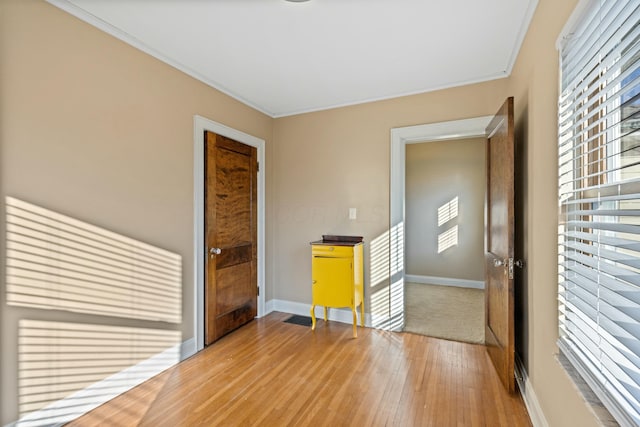 empty room with a healthy amount of sunlight, crown molding, and hardwood / wood-style flooring