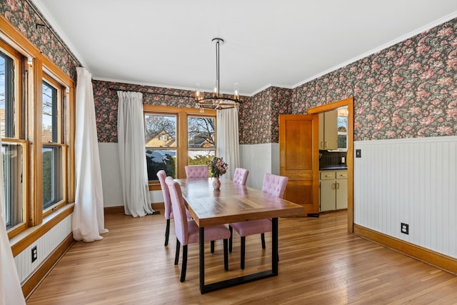 dining area with light hardwood / wood-style floors, crown molding, and an inviting chandelier