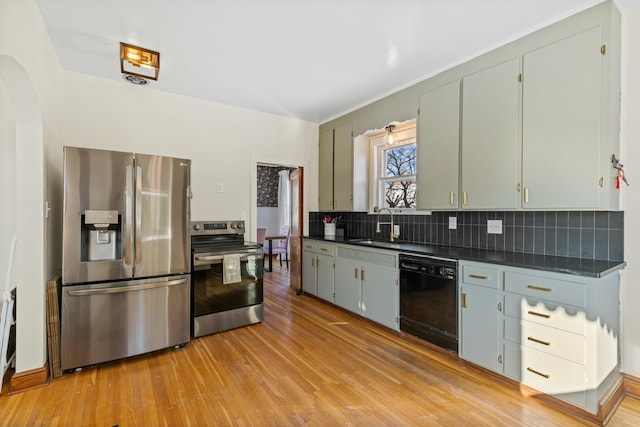 kitchen with light wood-type flooring, backsplash, sink, and stainless steel appliances