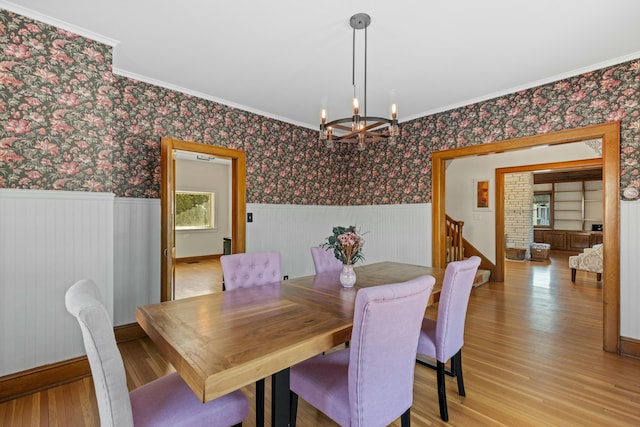 dining room with an inviting chandelier, crown molding, and light hardwood / wood-style floors