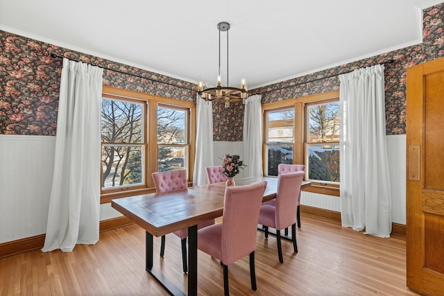 dining area featuring crown molding, light wood-type flooring, an inviting chandelier, and a healthy amount of sunlight