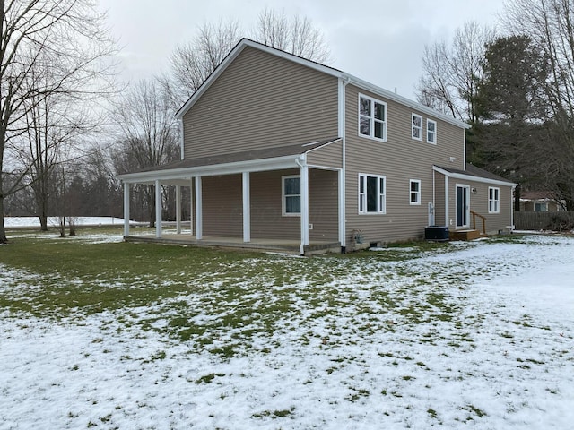 snow covered house featuring a porch and a yard