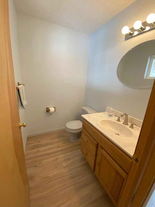 bathroom featuring hardwood / wood-style flooring, toilet, and vanity