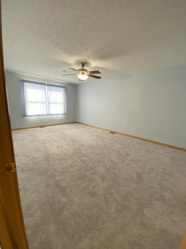 carpeted empty room with a textured ceiling and ceiling fan