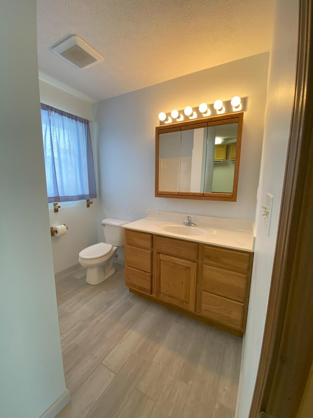 bathroom featuring hardwood / wood-style floors, toilet, vanity, and a textured ceiling