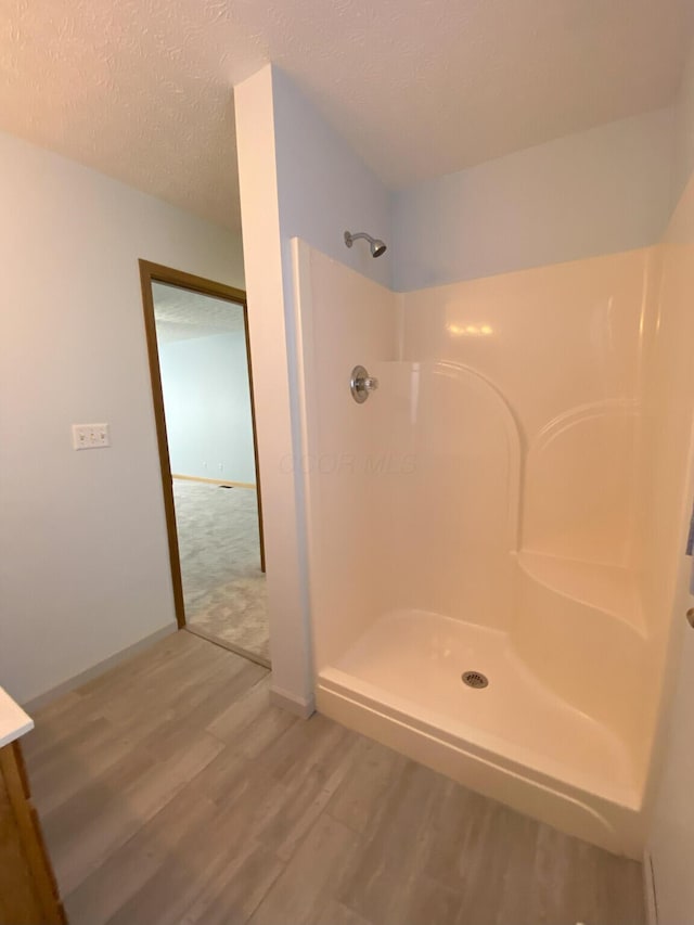 bathroom featuring a shower, hardwood / wood-style floors, and a textured ceiling