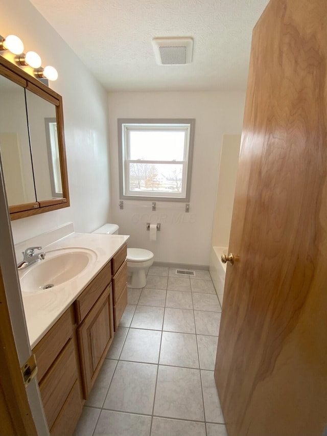 bathroom featuring vanity, toilet, a textured ceiling, and tile patterned flooring