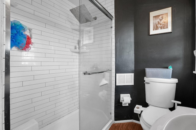 bathroom with wood-type flooring, a shower with shower door, and toilet