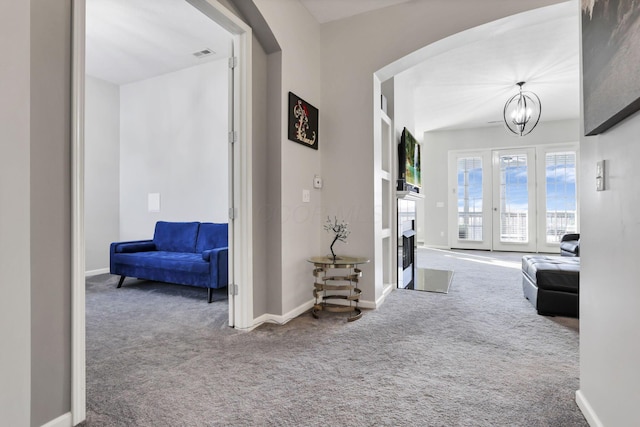 hall featuring carpet and a notable chandelier