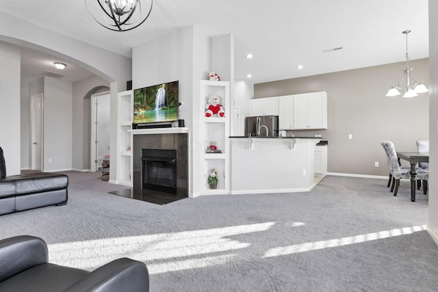 carpeted living room with built in shelves and a chandelier