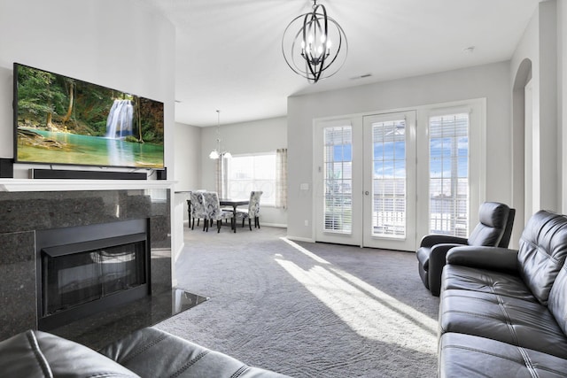 living room with a notable chandelier, dark colored carpet, and a tile fireplace