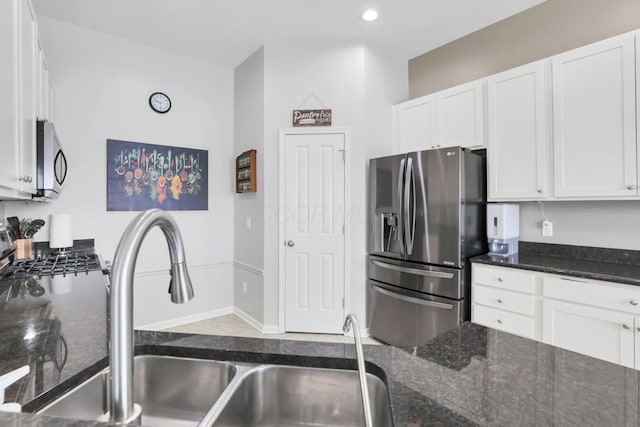 kitchen featuring white cabinets, dark stone counters, appliances with stainless steel finishes, and sink