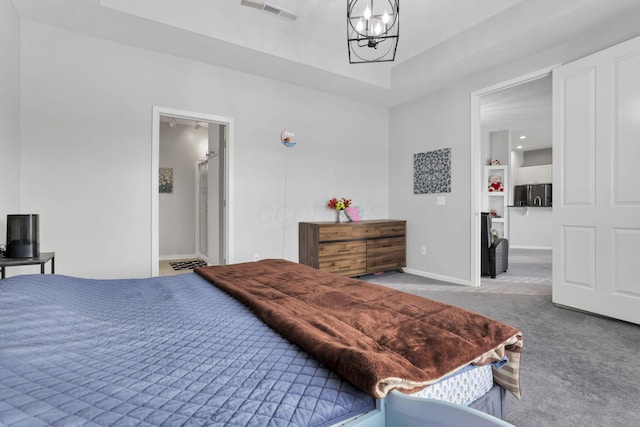 carpeted bedroom featuring a notable chandelier and a tray ceiling