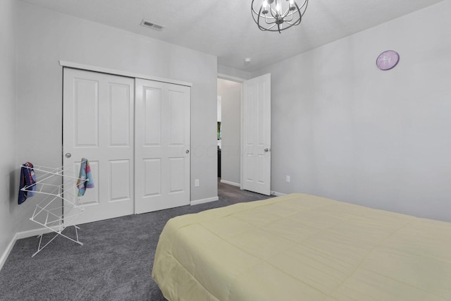 bedroom with a closet, a chandelier, and dark colored carpet