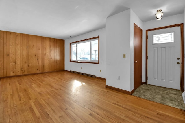 entryway with a baseboard radiator, a healthy amount of sunlight, wooden walls, and light hardwood / wood-style flooring