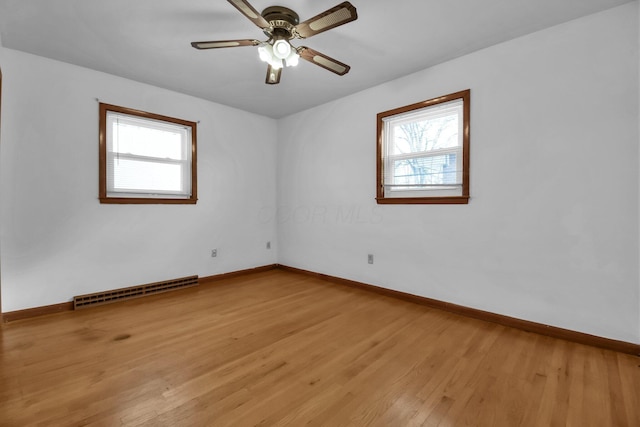 spare room with ceiling fan, wood-type flooring, and a healthy amount of sunlight