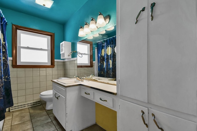 bathroom featuring a baseboard radiator, tile patterned floors, tile walls, toilet, and vanity