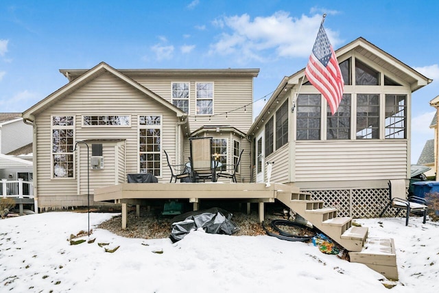 snow covered property featuring a wooden deck and a sunroom