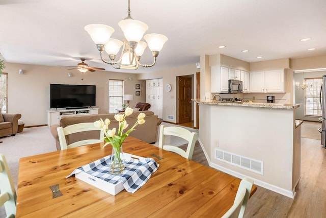 dining area featuring plenty of natural light, ceiling fan with notable chandelier, and light hardwood / wood-style floors