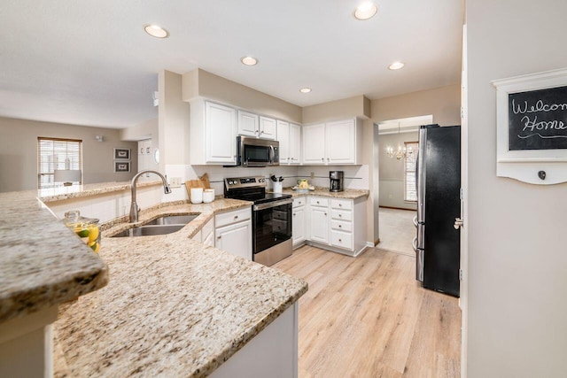 kitchen featuring sink, appliances with stainless steel finishes, white cabinetry, light stone counters, and kitchen peninsula