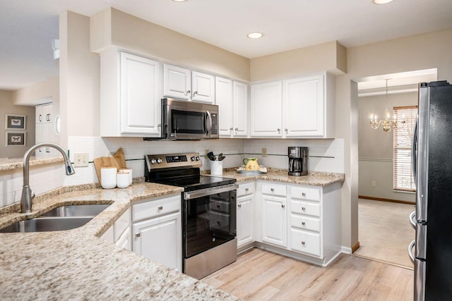 kitchen with sink, light stone counters, light hardwood / wood-style flooring, appliances with stainless steel finishes, and white cabinets