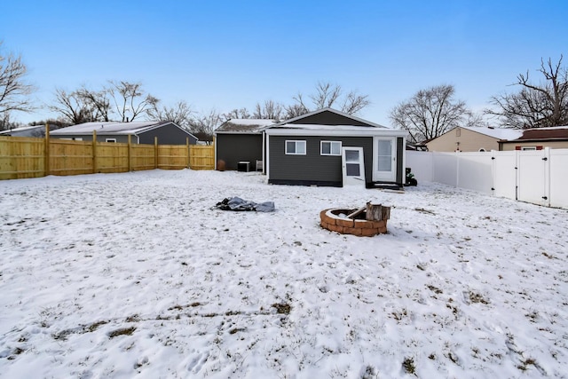 snow covered rear of property featuring a fire pit