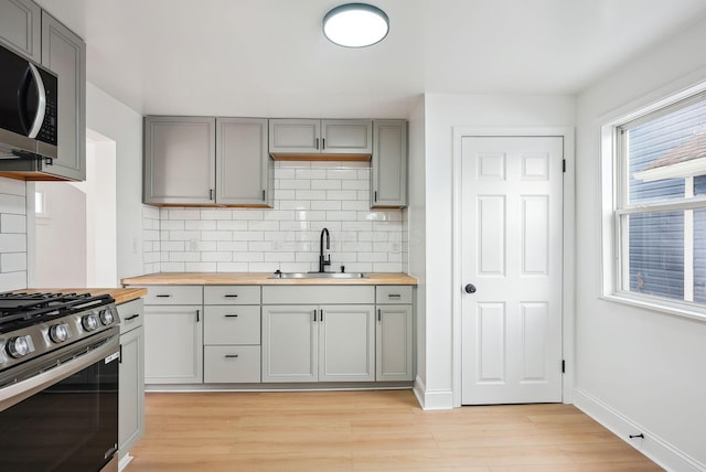 kitchen featuring appliances with stainless steel finishes, sink, backsplash, a wealth of natural light, and wood counters