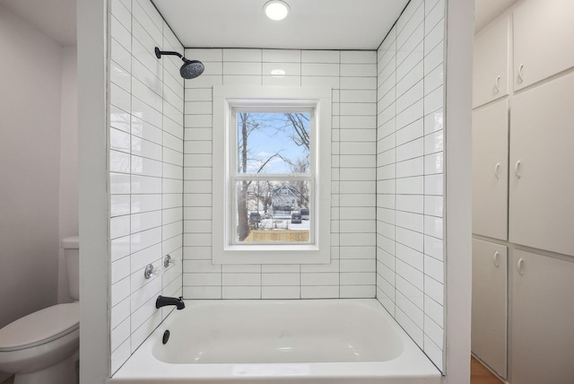 bathroom featuring toilet and tiled shower / bath combo