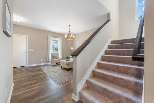 stairs with hardwood / wood-style flooring and a chandelier