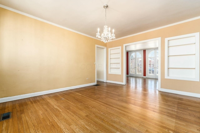 unfurnished room with wood-type flooring, a notable chandelier, crown molding, and built in shelves