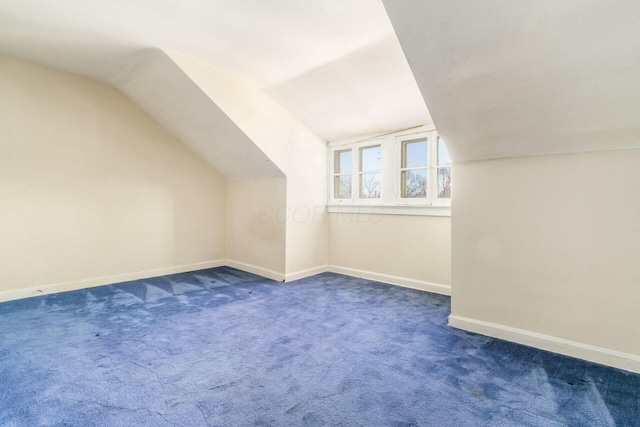 additional living space featuring dark colored carpet and vaulted ceiling