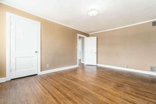 empty room with ornamental molding and hardwood / wood-style floors