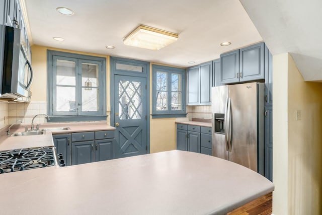 kitchen with sink, backsplash, stainless steel appliances, and kitchen peninsula