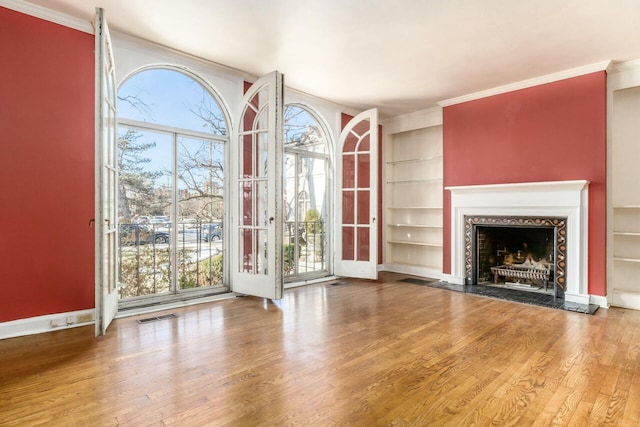 unfurnished living room with hardwood / wood-style flooring, ornamental molding, and built in features