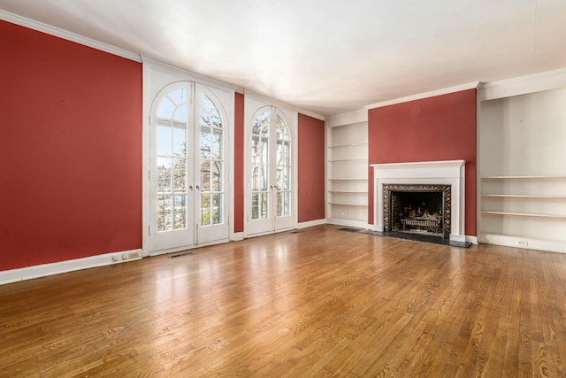 unfurnished living room featuring ornamental molding, hardwood / wood-style floors, and built in features