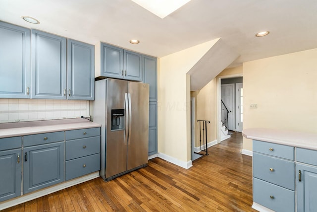 kitchen with dark wood-type flooring, blue cabinets, stainless steel fridge, and backsplash