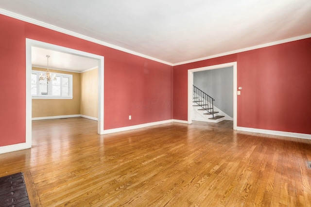 spare room with crown molding, hardwood / wood-style floors, and an inviting chandelier