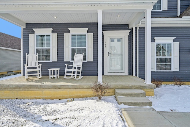 snow covered property entrance featuring a porch