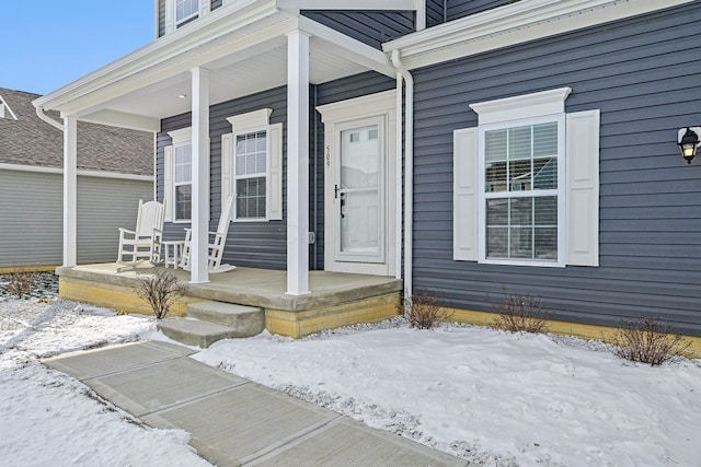 snow covered property entrance with covered porch