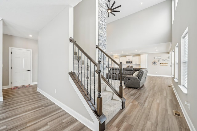 stairway featuring hardwood / wood-style flooring, a high ceiling, and ceiling fan