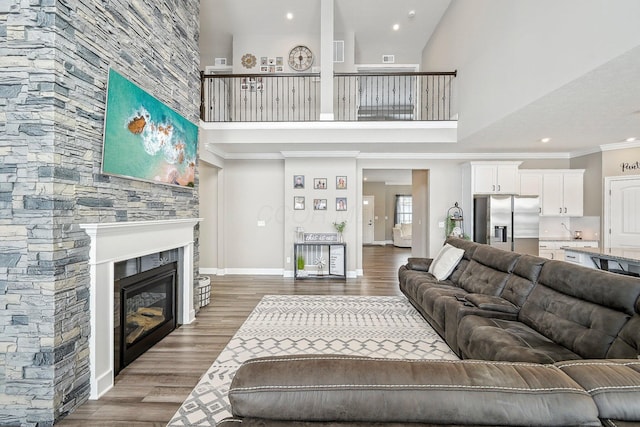 living room with hardwood / wood-style flooring, crown molding, a towering ceiling, and a fireplace