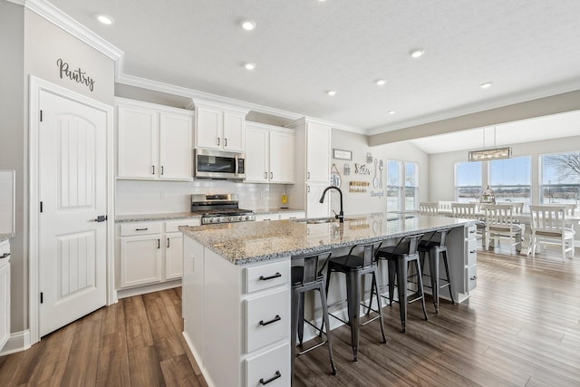 kitchen with sink, white cabinetry, appliances with stainless steel finishes, and an island with sink